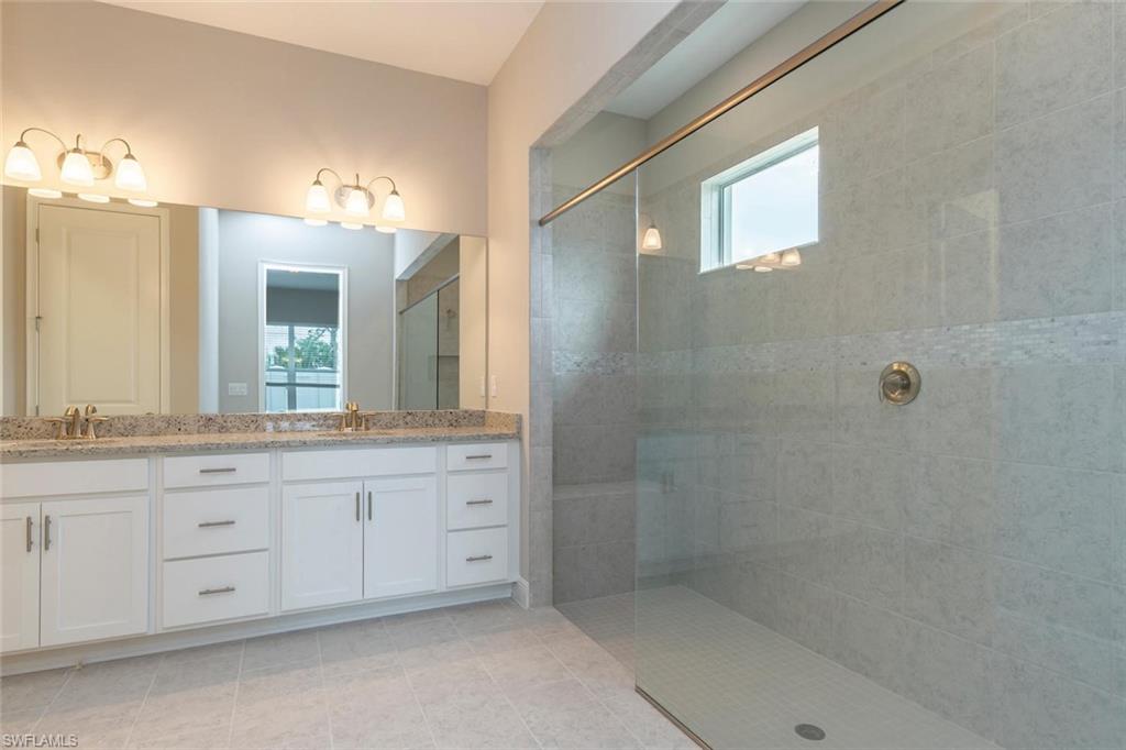 3509 Pilot Circle Naples, FL 34120 - Photo 19 of 32 a bathroom with a granite countertop sink a mirror and a shower