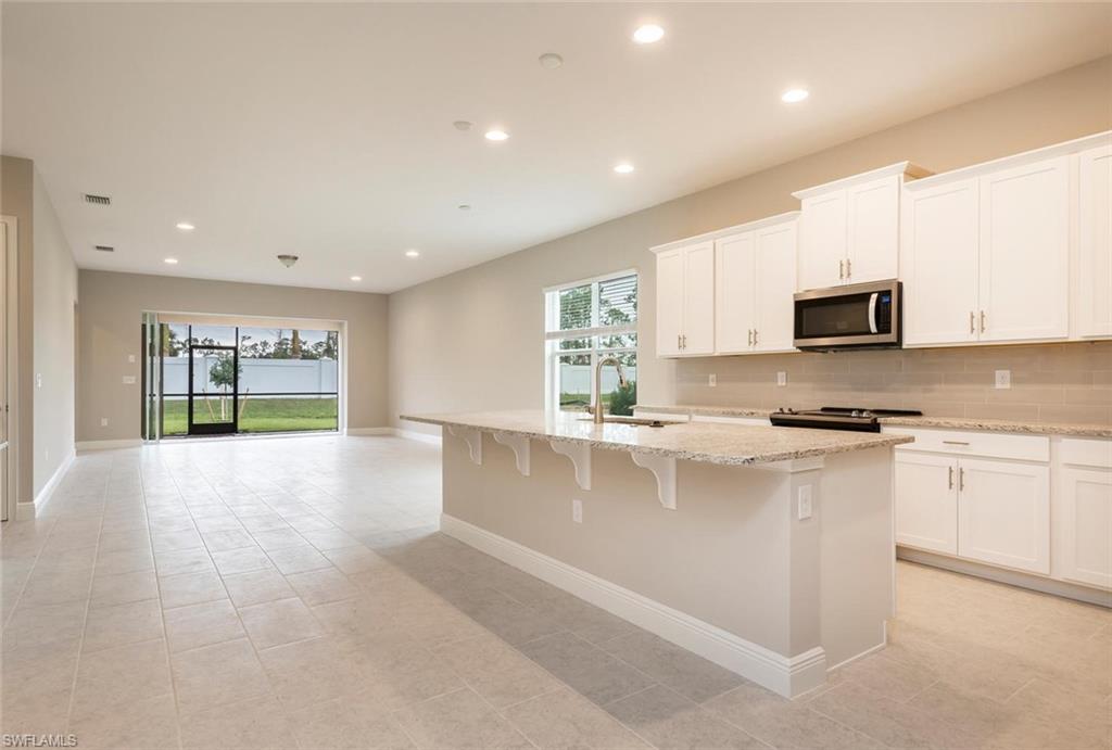 3509 Pilot Circle Naples, FL 34120 - Photo 10 of 32 a large kitchen with stainless steel appliances granite countertop a stove a sink and a microwave