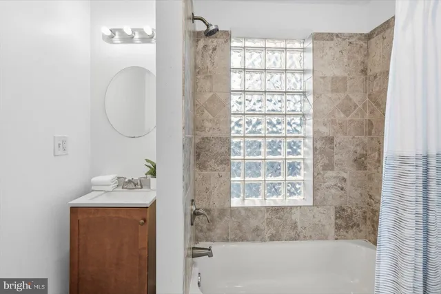 a bathroom with a granite countertop sink a vanity and a bathtub