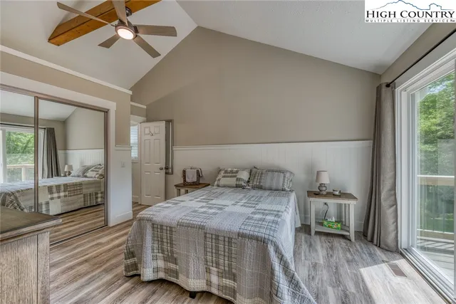 a bedroom with a bed and a large window with wooden floor