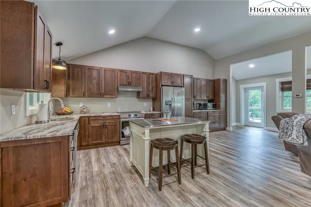 a kitchen with stainless steel appliances granite countertop wooden floors a stove a sink and a refrigerator