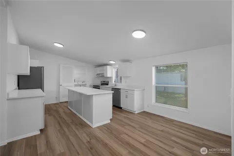 a open kitchen with white cabinets and wooden floor
