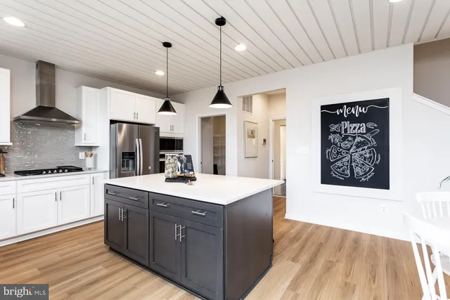 a kitchen with stainless steel appliances kitchen island granite countertop a sink stove and refrigerator