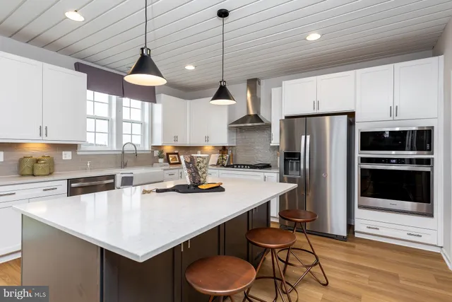 a kitchen with stainless steel appliances a sink a stove a refrigerator a center island and cabinets