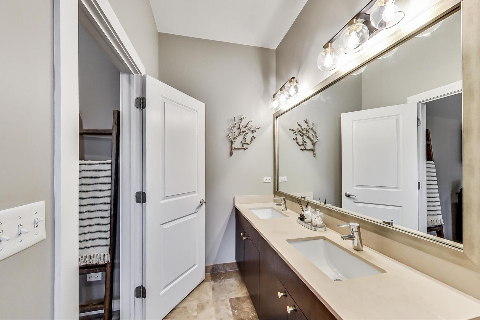1256 North Cleaver Street, Unit 2E Chicago, IL 60642 - Photo 13 of 18 a bathroom with a double vanity sink a mirror and a shower