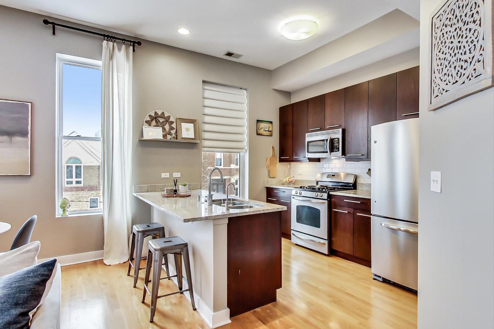 1256 North Cleaver Street, Unit 2E Chicago, IL 60642 - Photo 7 of 18 a kitchen with cabinets stainless steel appliances and a dining table