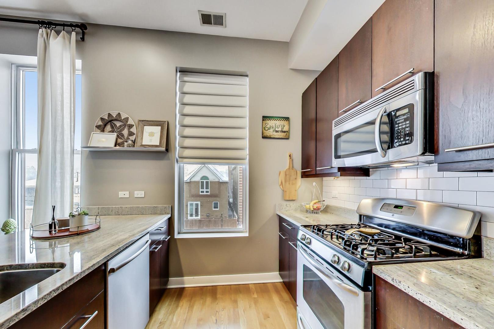 1256 North Cleaver Street, Unit 2E Chicago, IL 60642 - Photo 8 of 18 a kitchen with granite countertop a stove a sink and a microwave
