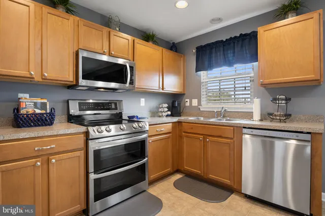 a kitchen with stainless steel appliances granite countertop a sink a stove a microwave and wooden cabinets
