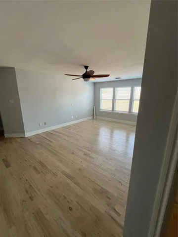 a view of a big room with wooden floor and windows
