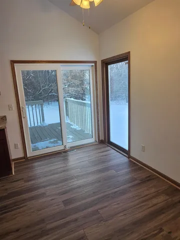 a view of an empty room with wooden floor and a window