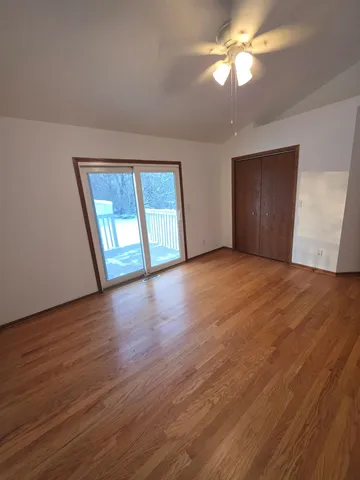 a view of empty room with wooden floor and fan