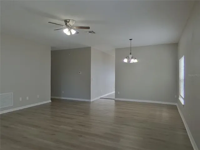an empty room with wooden floor chandelier and entryway
