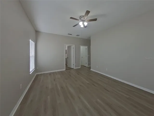 a view of an empty room with chandelier fan