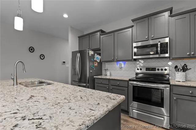a kitchen with granite countertop a stove top oven microwave and refrigerator
