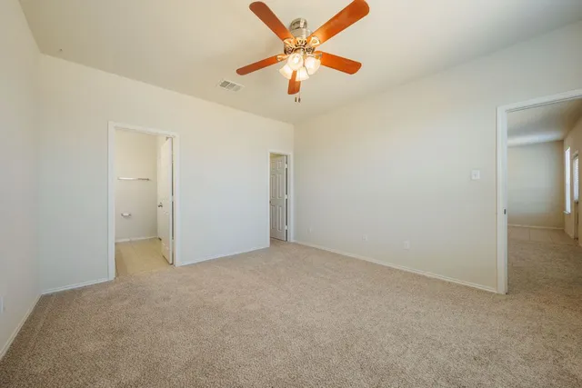 an empty room with closet and a chandelier fan