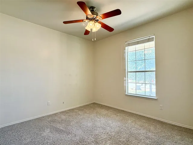 an empty room with a window and a ceiling fan