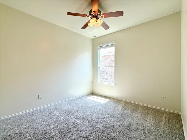 an empty room with a chandelier fan and windows