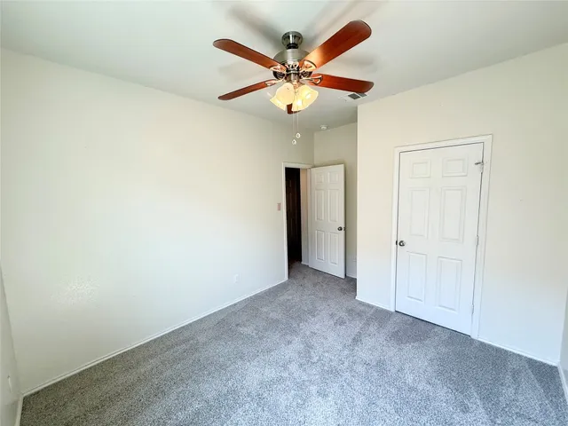an empty room with chandelier fan and a ceiling fan