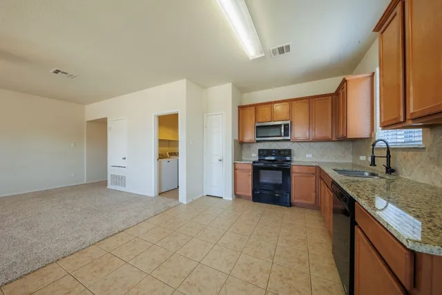 a kitchen with stainless steel appliances granite countertop a stove a sink and a refrigerator