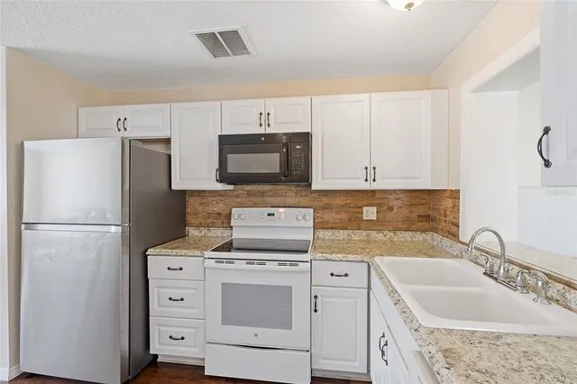 a kitchen with appliances a sink and cabinets