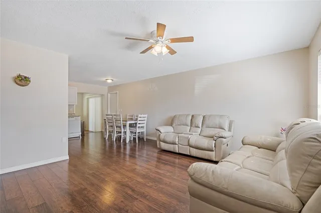 a living room with furniture and a dining table with wooden floor