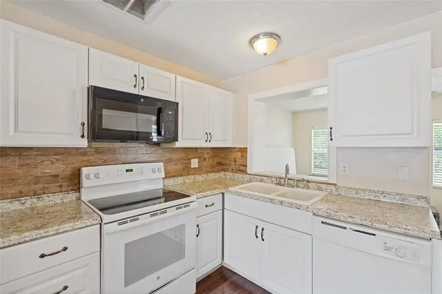 a kitchen with granite countertop a sink stainless steel appliances and white cabinets