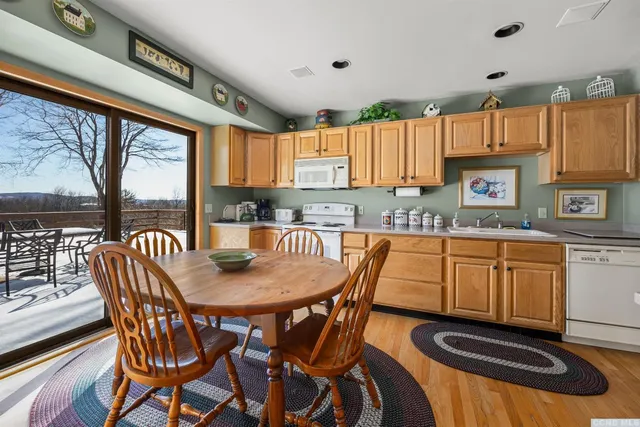 a kitchen with stainless steel appliances granite countertop a table chairs and a wooden cabinets
