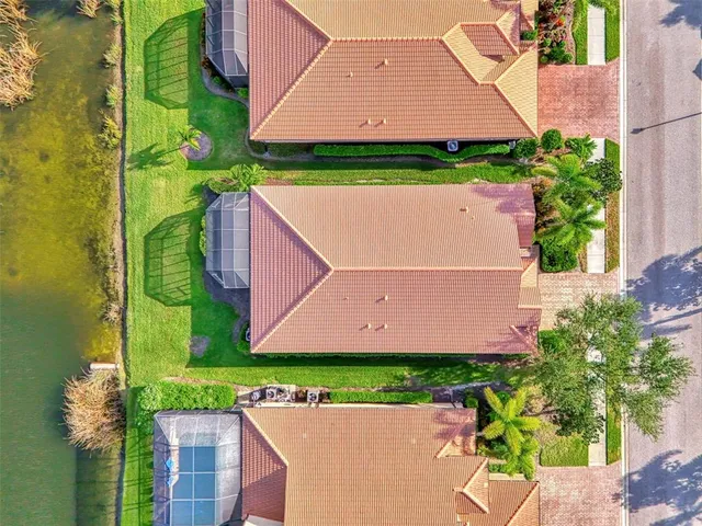 a view of a white house with large windows and a yard with plants