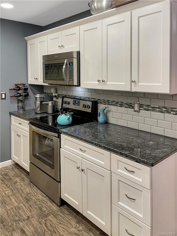 a kitchen with granite countertop white cabinets white stainless steel appliances and a sink