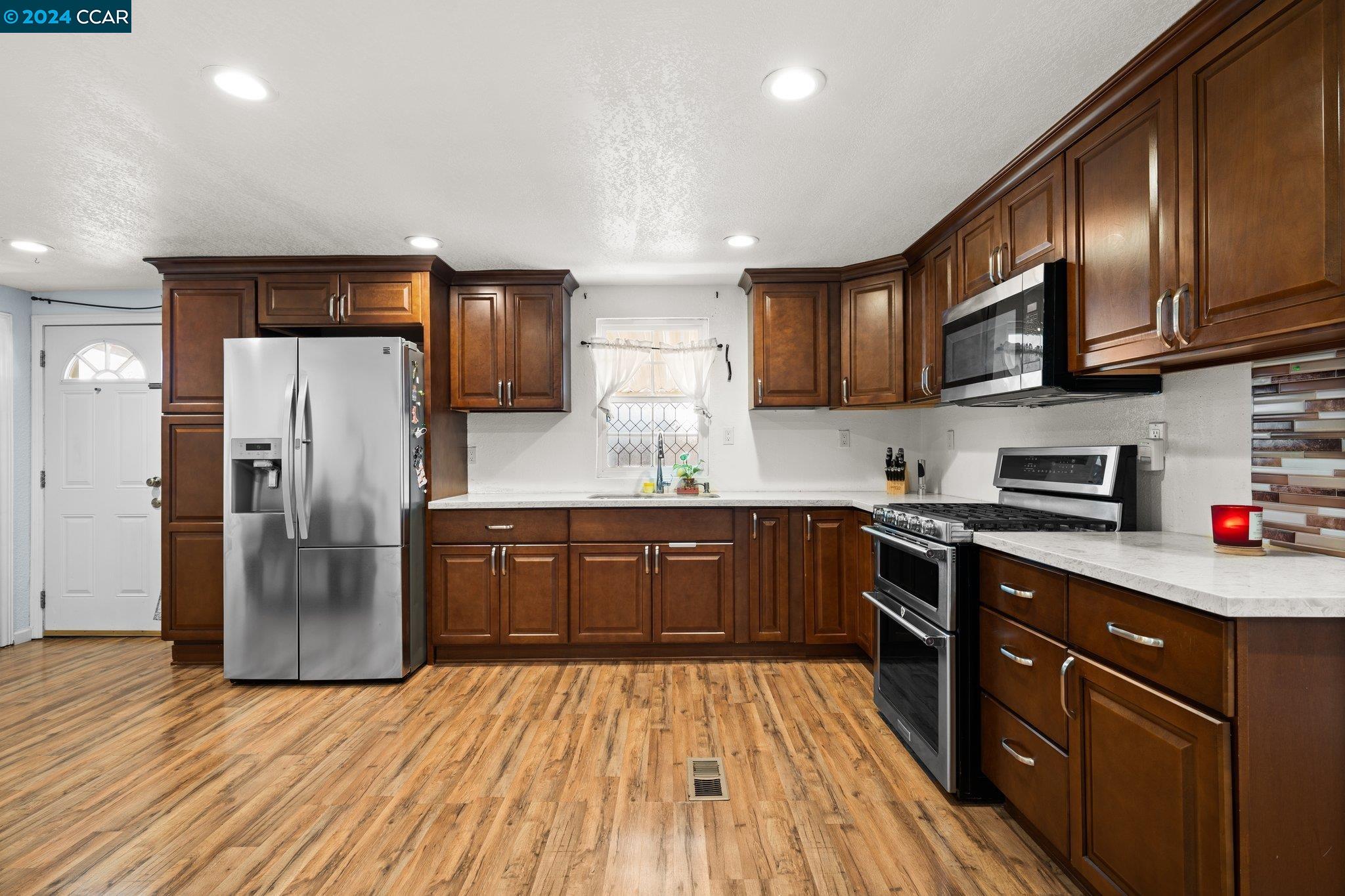 55 Pacifica Avenue, Unit 51 Bay Point, CA 94565 - Photo 10 of 35 a kitchen with stainless steel appliances granite countertop wooden cabinets a refrigerator a sink and dishwasher a oven with wooden floors