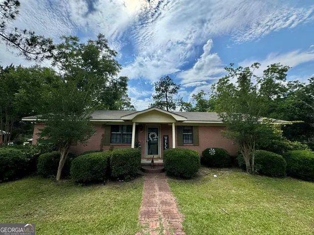 a view of a house with backyard garden and a tree