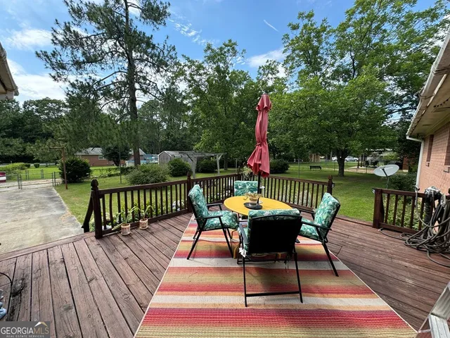 a view of a roof deck with table and chairs a barbeque with wooden floor and fence