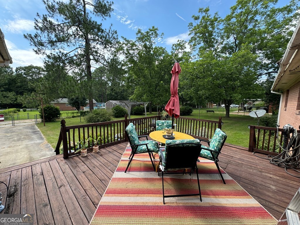 2014 Davis Avenue Tifton, GA 31794 - Photo 2 of 18 a view of a roof deck with table and chairs a barbeque with wooden floor and fence