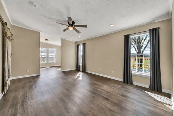 a view of a big room with wooden floor kitchen view and windows