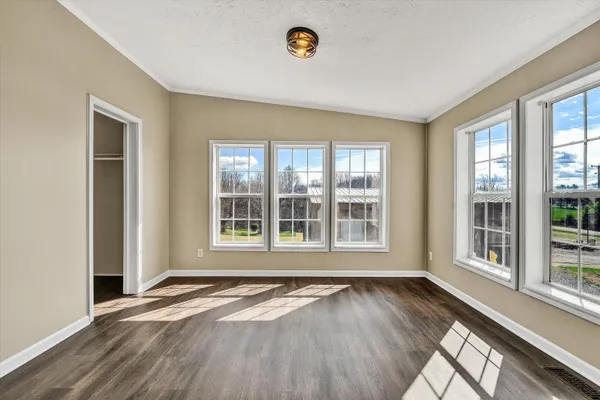 a view of empty room with wooden floor and ceiling fan