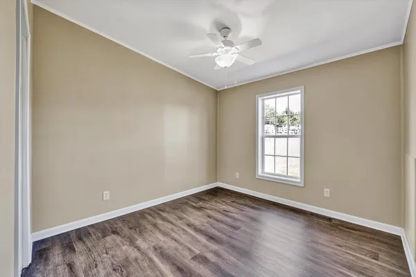 a view of empty room with wooden floor and fan
