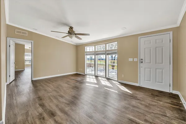 a view of an empty room with a window and wooden floor