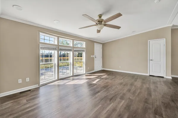 a view of an empty room with a window and wooden floor