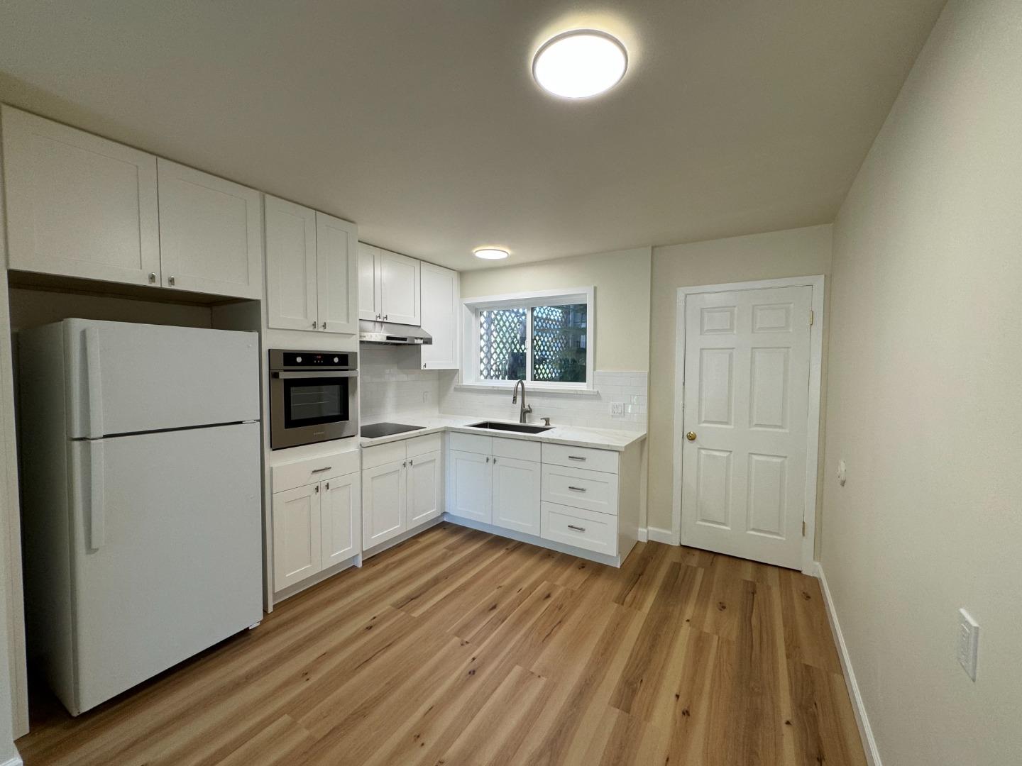 370 Bartlett Street, Unit 3 San Francisco, CA 94110 - Photo 14 of 35 a kitchen with a refrigerator a sink and dishwasher with wooden floor