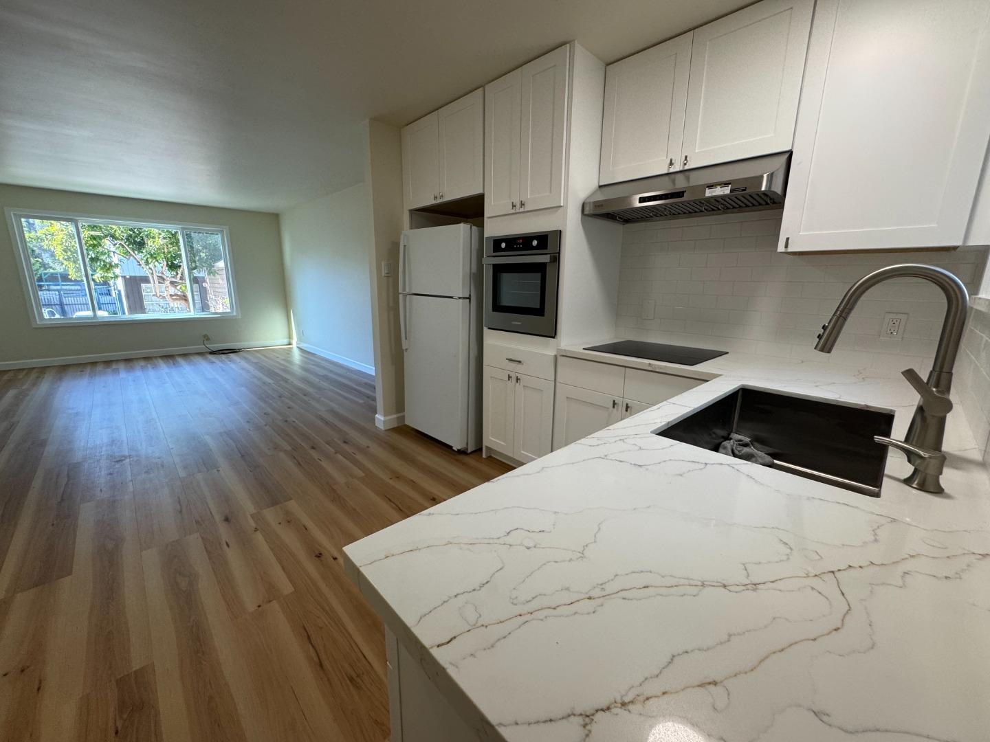 370 Bartlett Street, Unit 3 San Francisco, CA 94110 - Photo 18 of 35 a kitchen with a wooden floor white cabinets and stainless steel appliances
