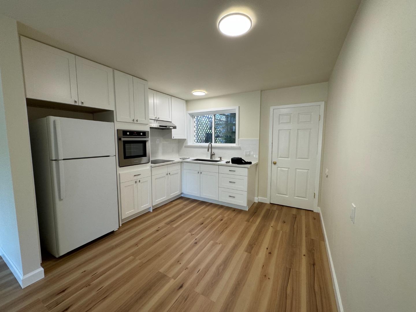 370 Bartlett Street, Unit 3 San Francisco, CA 94110 - Photo 24 of 35 a kitchen with white cabinets and wooden floor