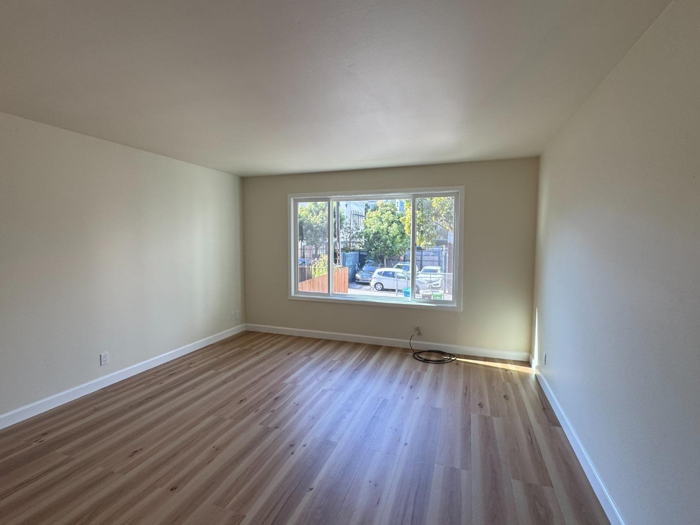 370 Bartlett Street, Unit 3 San Francisco, CA 94110 - Photo 5 of 35 an empty room with wooden floor and windows