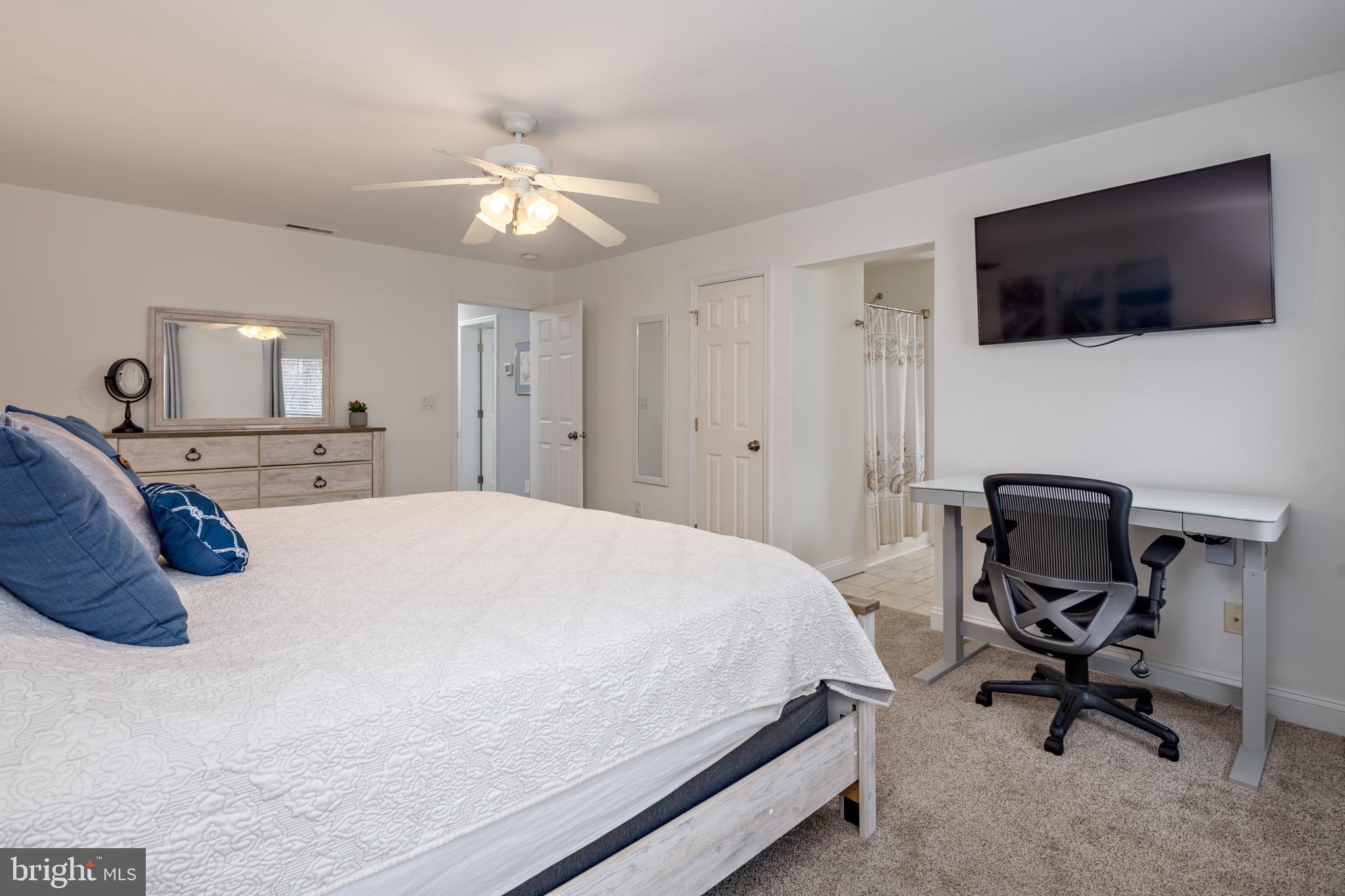 326 South Carolina Road Stevensville, MD 21666 - Photo 19 of 48 a spacious bedroom with a bed a flat screen tv and a chandelier