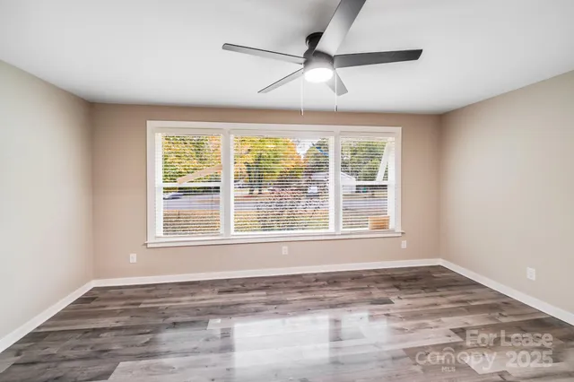 a view of an empty room with a window and wooden floor