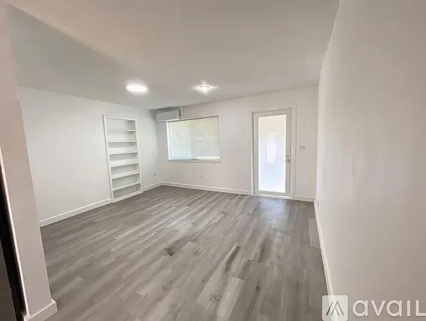 an empty room with wooden floor and window