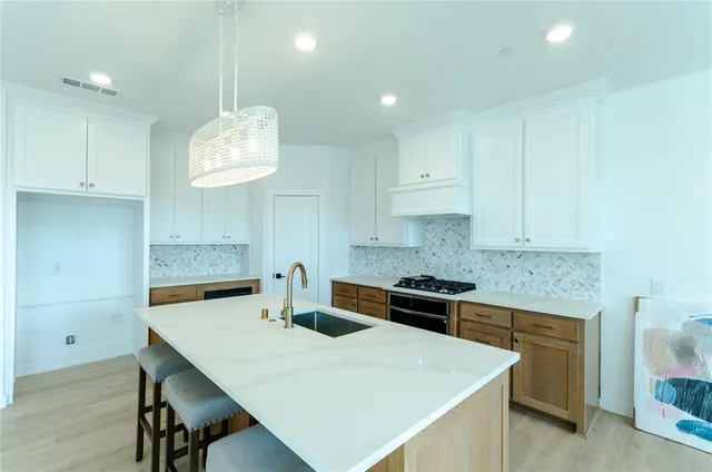 a kitchen with kitchen island granite countertop a sink a stove and cabinets