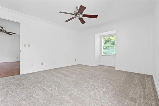 an empty room with ceiling fan and window
