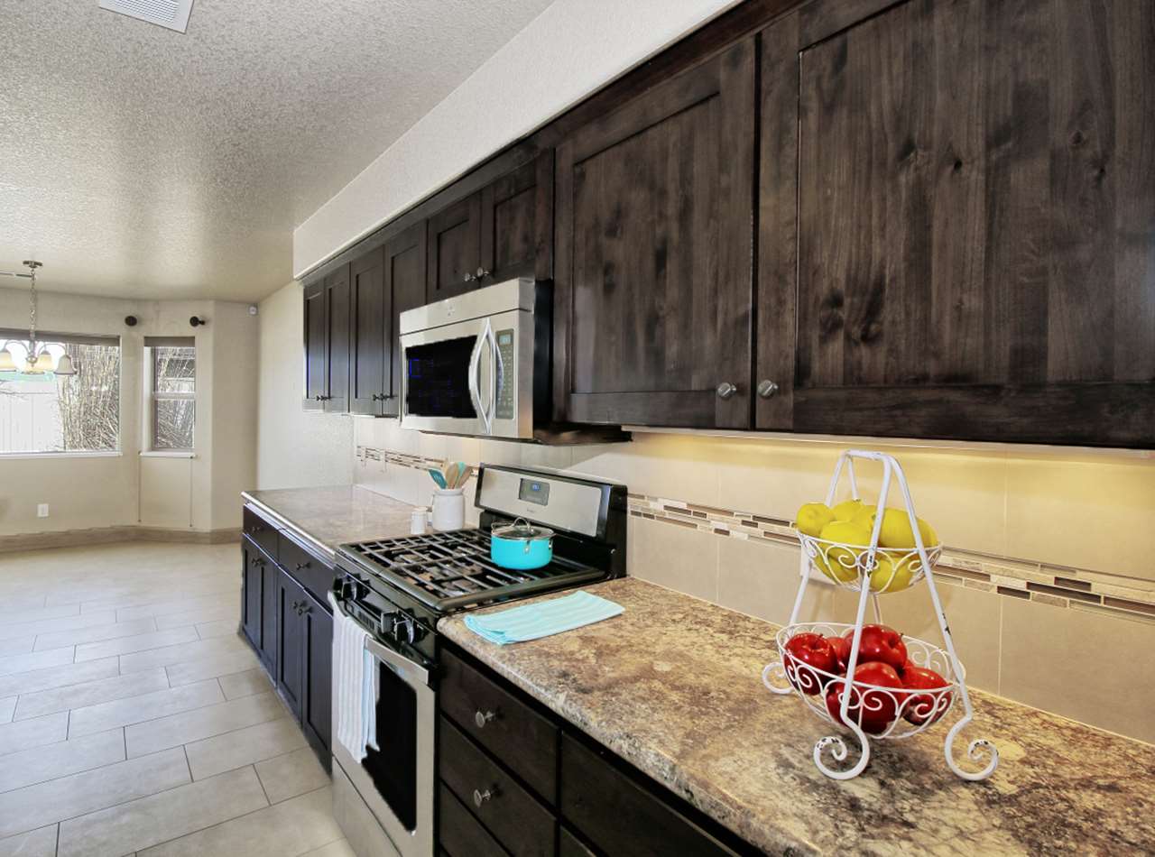 199 Red Rocks Street Fruita, CO 81521 - Photo 8 of 25 a kitchen with granite countertop a stove a sink and a microwave