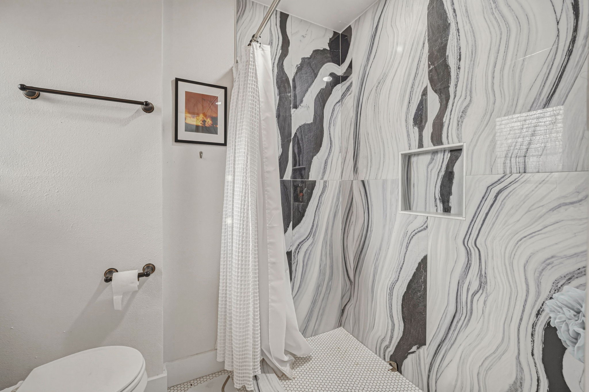 5332 Balcones Drive, Unit B Austin, TX 78731 - Photo 10 of 15 Bathroom featuring a shower with unique black and white patterned tile walls, a built-in shower niche, and a white hexagonal tile floor