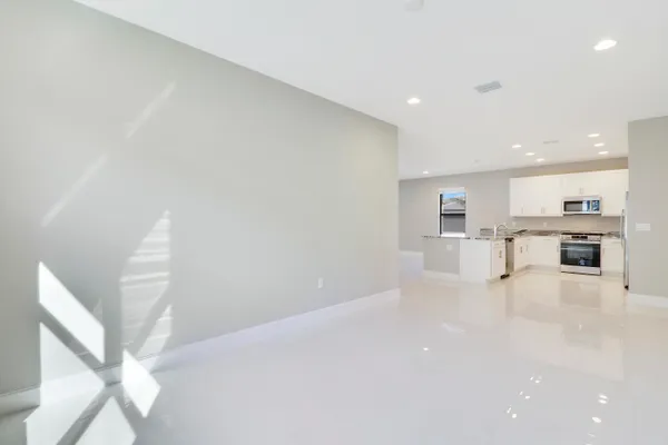 a view of kitchen with kitchen island a sink stainless steel appliances white cabinets and a refrigerator